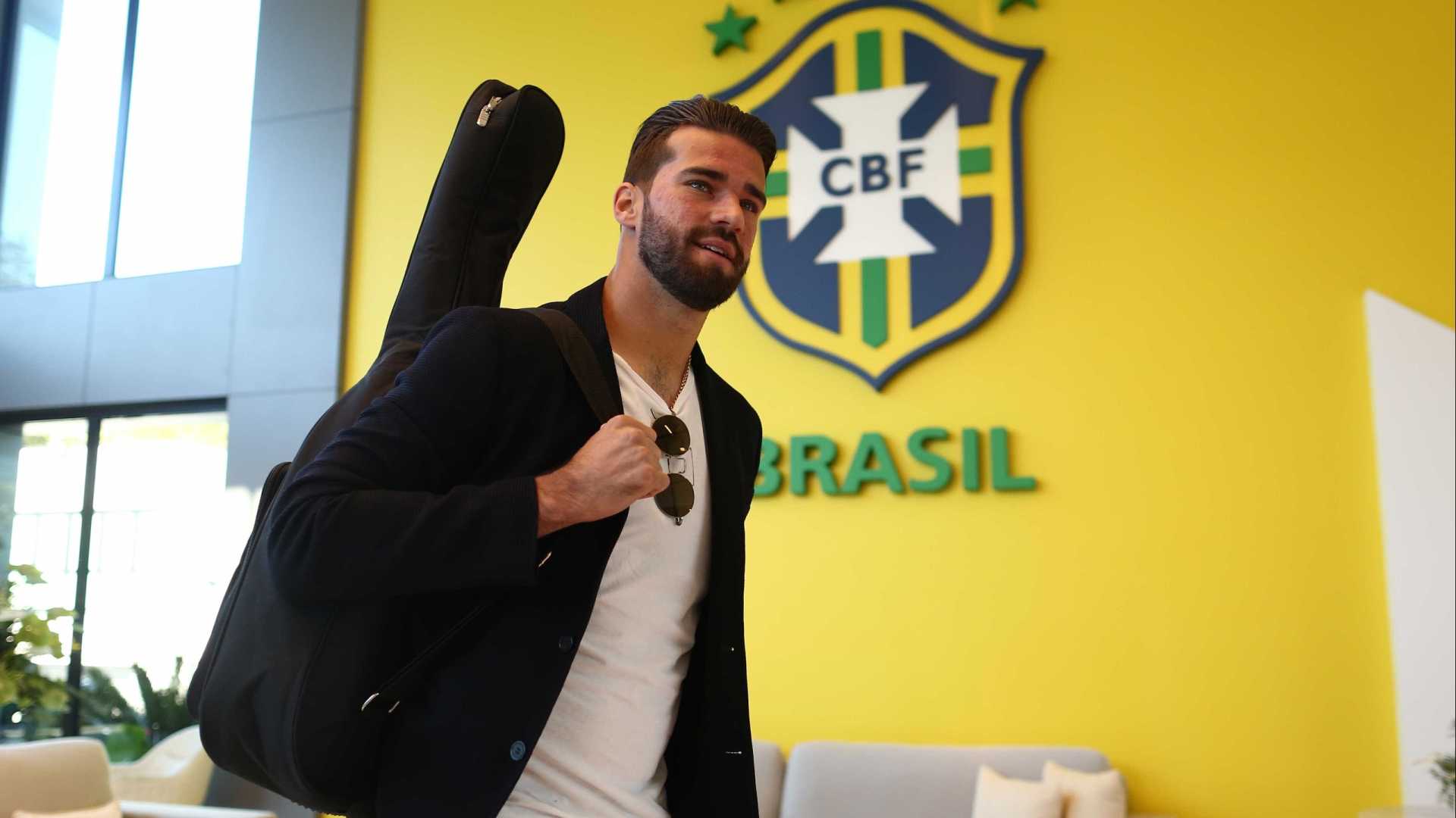 Com violão nas costas, Alisson se apresenta à seleção em Teresópolis